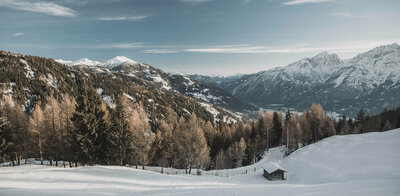 Spuren im Schnee an einem Berg mit Aussicht auf den verschneiten Lienzer Talboden.