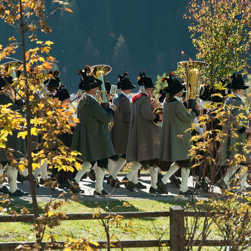 Zwischen zwei verfärbten Bäume sieht man Häuser eines Dorfes.
