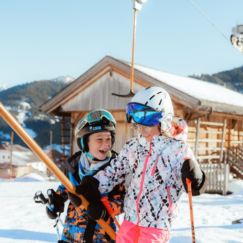 Kinderland Obertilliach Skifahren '22 Zwei Kinder lassen sich vom Schlepplift im Familienskigebiet Golzentipp in Obertilliach auf den Berg ziehen.