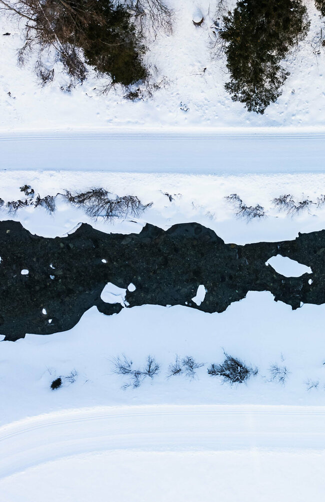 Blick auf die Langlaufloipe in Prägraten aus der Vogelperspektive mit dem daneben vorbeilaufenden Bach.