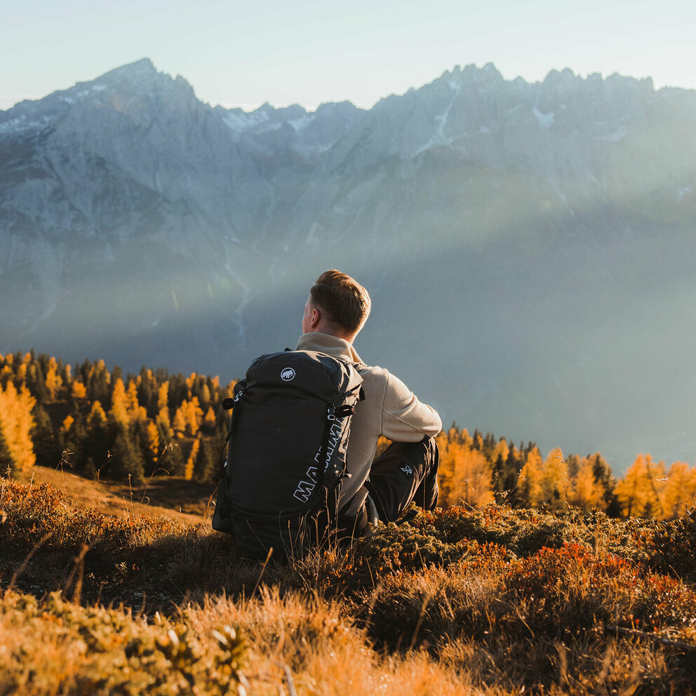 Wanderer genießt am Ederplan die Aussicht in die umliegende Berglandschaft im goldenen Herbst.
