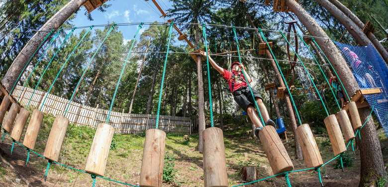 Junger Bub hantelt sich geschickt durch eine Station im Hochseilgarten Galitzenklamm