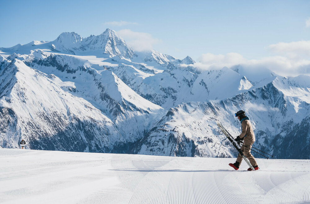 Winterliches Panorama mit dem Großglockner im Hintergrund und einem Skifahrer im Vordergrund, der sich gerade bereit macht, in seine Ski zu steigen.