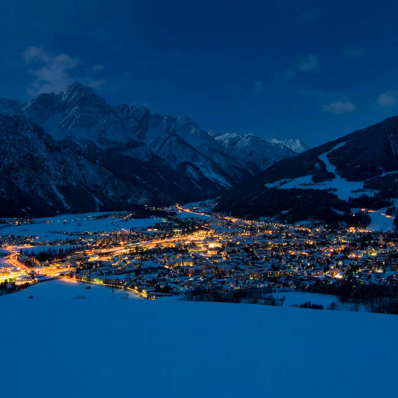 Blick auf den Lienzer Talboden in einer klaren Winternacht. Die Lichter der Stadt erhellen die Nacht.