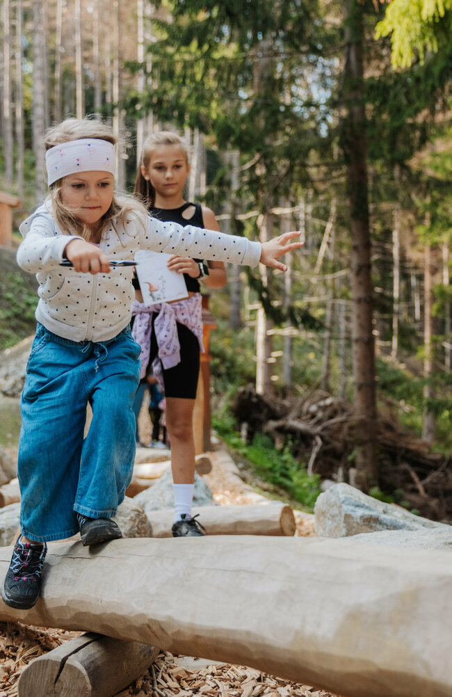 Ein Mädchen balanciert im Wichtelpark über eine hölzerne Konstruktion.