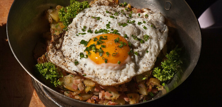 Tiroler Gröstl mit Spiegelei und Schnittlauch in einer kleine Eisenpfanne.