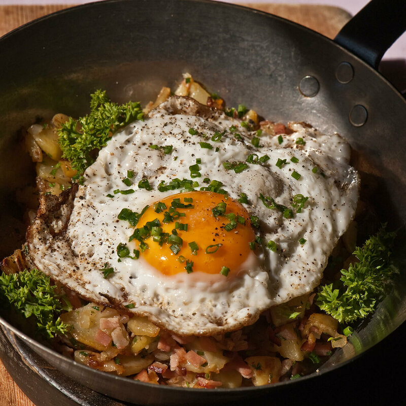 Tiroler Gröstl mit Spiegelei und Schnittlauch in einer kleine Eisenpfanne.