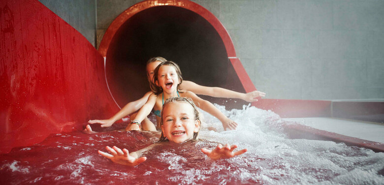 Dolomitenbad Lienz Drei Mädchen am Ausgang einer roten Wasserrutsche im Dolomitenbad in Lienz.