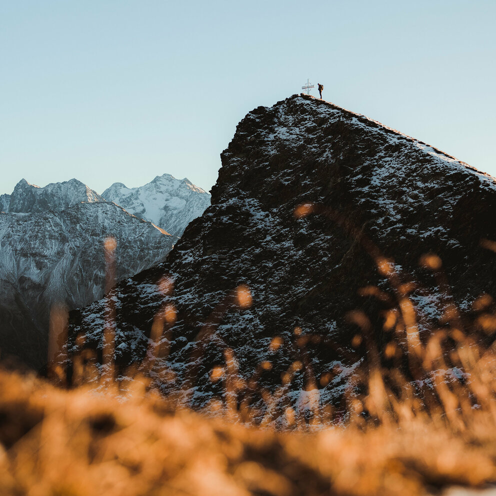 Figerhorn Wanderer am Gipfel des Figerhorns im Herbst mit schon einigen Schneefeldern auf den Bergen.