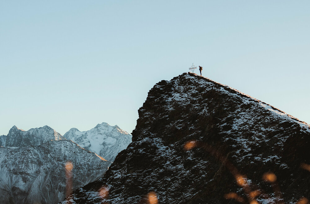 Wanderer am Gipfel des Figerhorns im Herbst mit schon einigen Schneefeldern auf den Bergen.