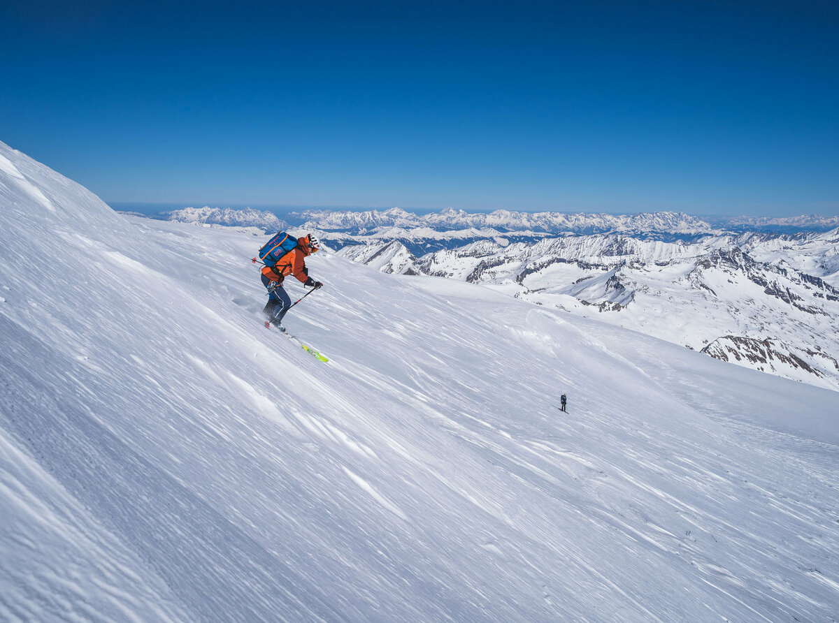 Ein Skifahrer bei der Abfahrt Richtung Venedigerscharte mit Bergkulisse und blauem Himmel.