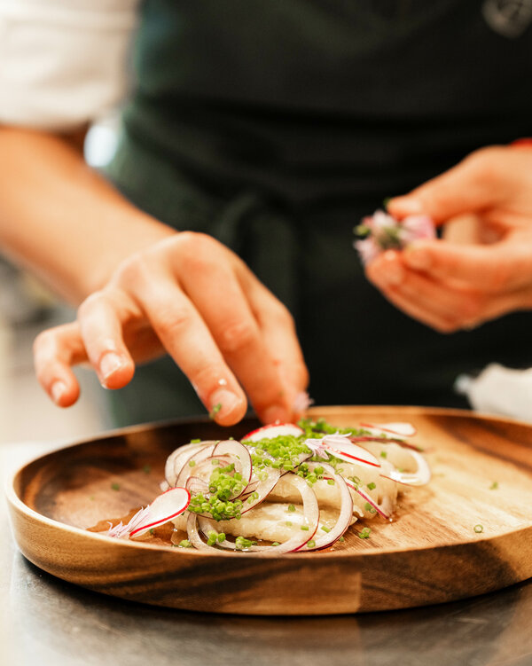 Kräuter-Topfen-Ravioli Köchin bereitet einen Holzeller mit Kräuter-Topfen-Ravioli vor.