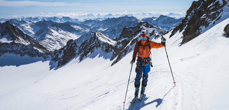 Skitourengeher mit orangener Jacke und Blick auf die kleine südliche Malhamkees mit den Dolomiten im Hintergrund.