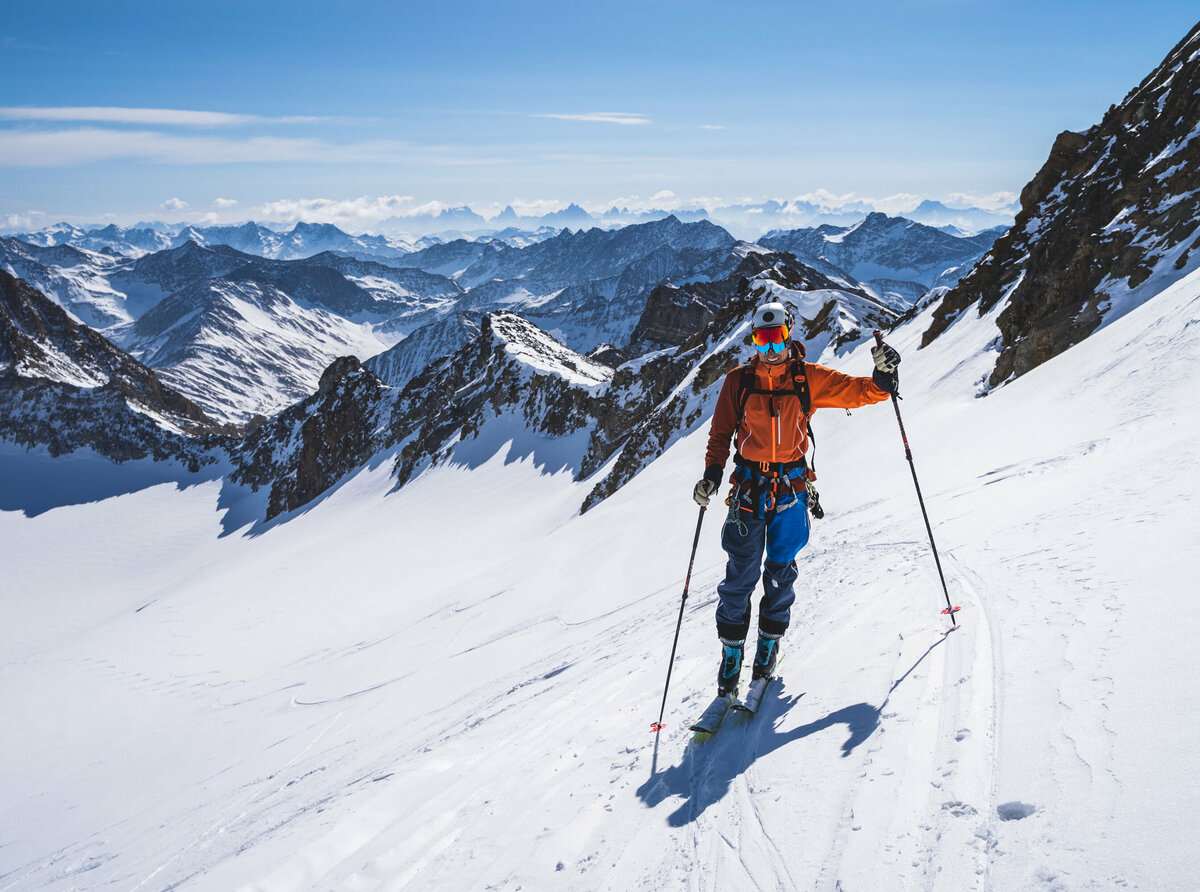 Skitourengeher mit orangener Jacke und Blick auf die kleine südliche Malhamkees mit den Dolomiten im Hintergrund.