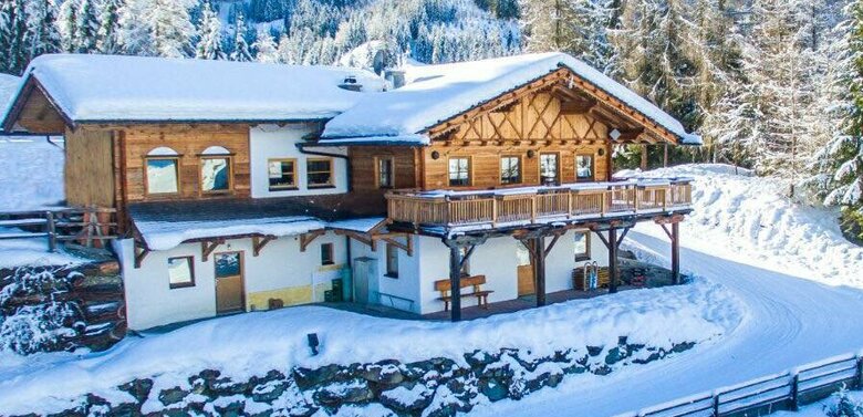 Die schöne Wuerfelehuette ist dick mit Schnee bedeckt. Direkt davor verläuft der Rodelweg.