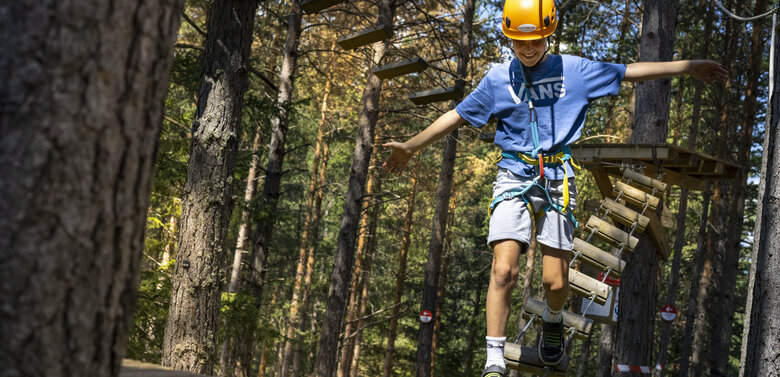 junger Kletterer im Kletterpark Moosalm Ein junger Kletterer zeigt seine Geschicklichkeit im Kletterpark Moosalm in Lienz in Osttirol.