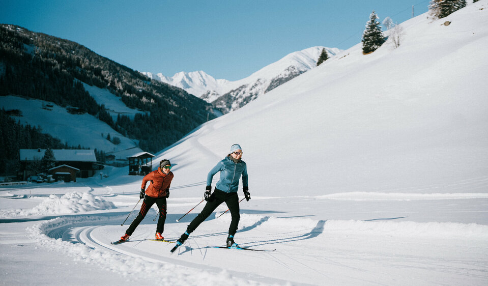 Zwei Langläufer:innen bei perfekten Loipen- und Wetterbedingungen in Innervillgraten.