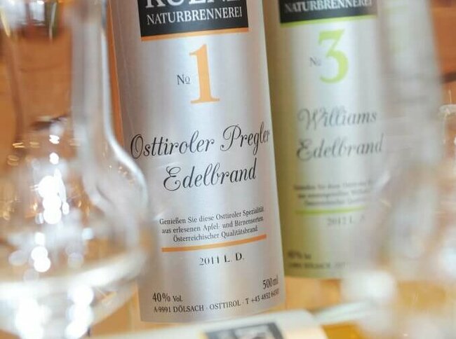 Vor zwei Flaschen Osttiroler Pregler liegt eine Flasche und davor ist ein leeres Schnapsglas anschaulich positioniert.
