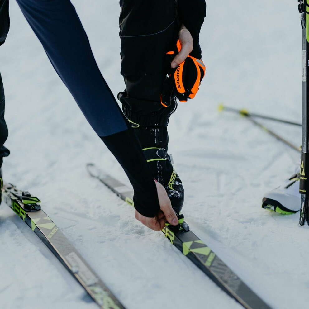 Nahaufnahme eines Langläufers beim Justieren seiner Langlaufskier in Obertilliach.