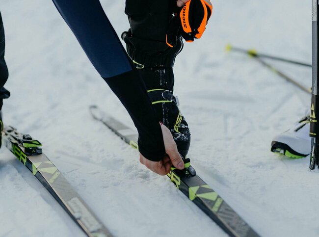 Nahaufnahme eines Langläufers beim Justieren seiner Langlaufskier in Obertilliach.