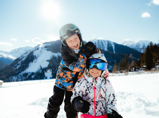 Zwei Kindern haben in der Winterlandschaft in Obertilliach Spaß.
