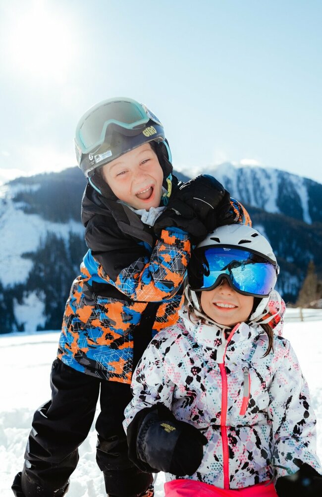 Zwei Kindern haben in der Winterlandschaft in Obertilliach Spaß.