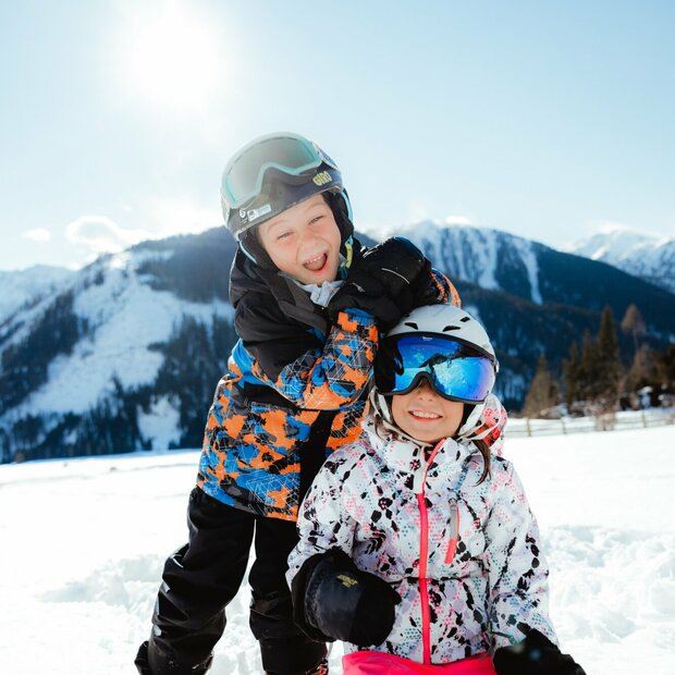 Zwei Kindern haben in der Winterlandschaft in Obertilliach Spaß.