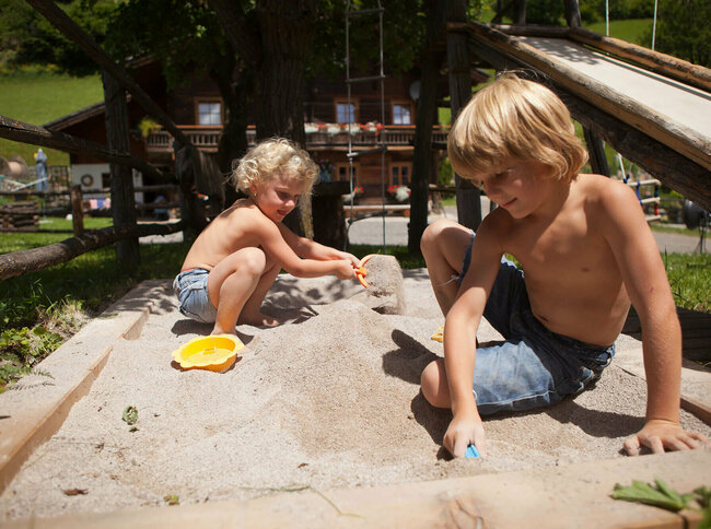 Urlaub am Bauernhof Zwei Kinder spielen im Sand auf einem Bauernhof.