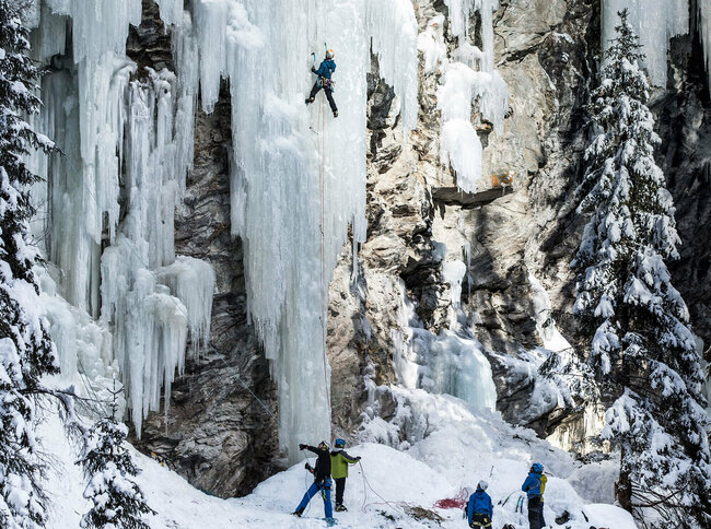 Eiskletterpark Osttirol Auf einem gefrorenen Wasserfall klettern mehrere Menschen hoch