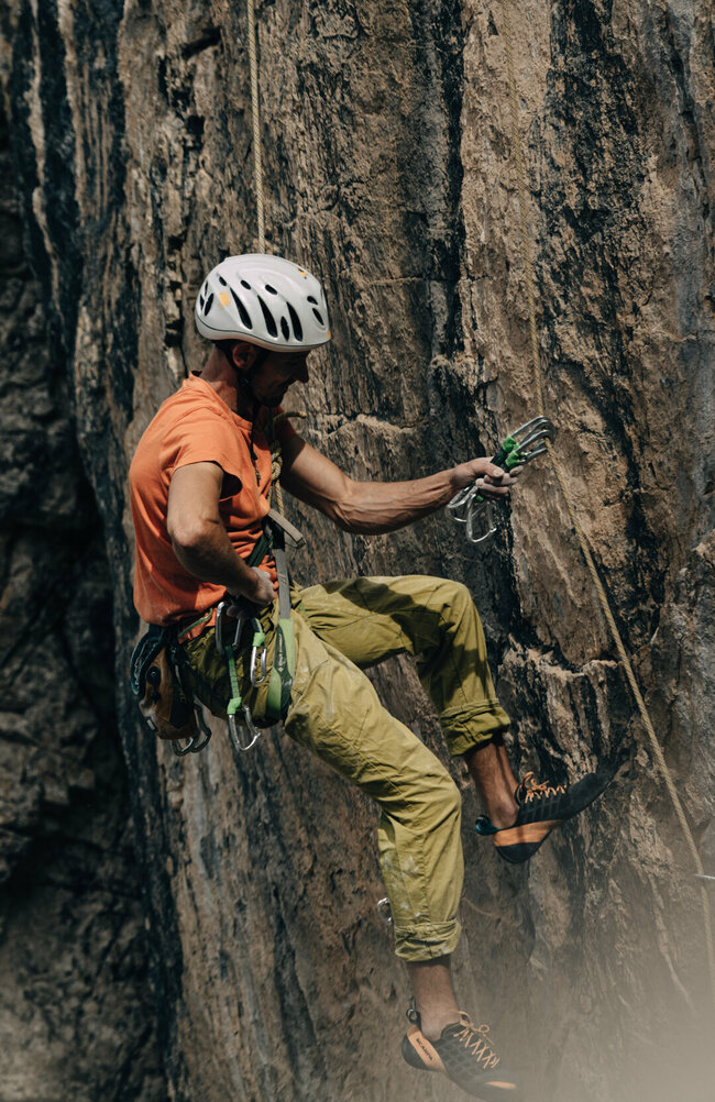 Ein Kletterer mit Kletterausrüstung hängt im Seil auf der Kletterwand im Laserzgebiet.