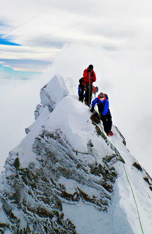 Zwei Bergsteiger:innen erklimmen den Gipfle des Kleinglockner