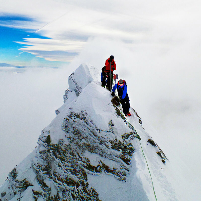 Zwei Bergsteiger:innen erklimmen den Gipfle des Kleinglockner