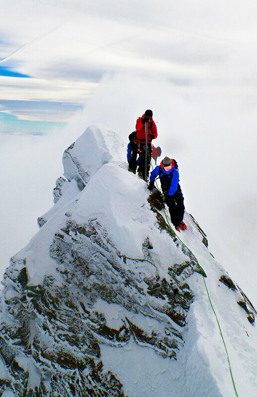 Zwei Bergsteiger:innen erklimmen den Gipfle des Kleinglockner