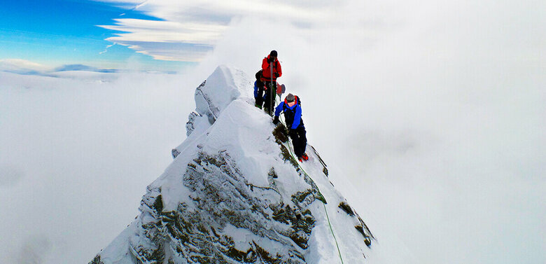 Zwei Bergsteiger:innen erklimmen den Gipfle des Kleinglockner