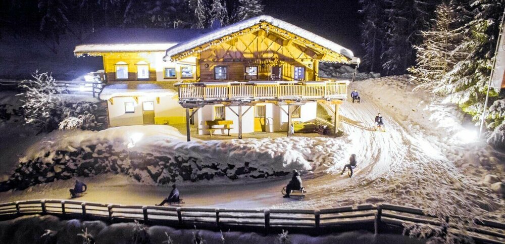 Rodelbahn Würfelehütte mit hell erleuchteter Hütte