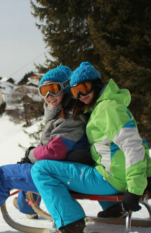 Kurzer Zwischenstop beim Rodeln in Obertilliach mit dem Dorf und der markanten Pfarrkirche im Hintergrund.