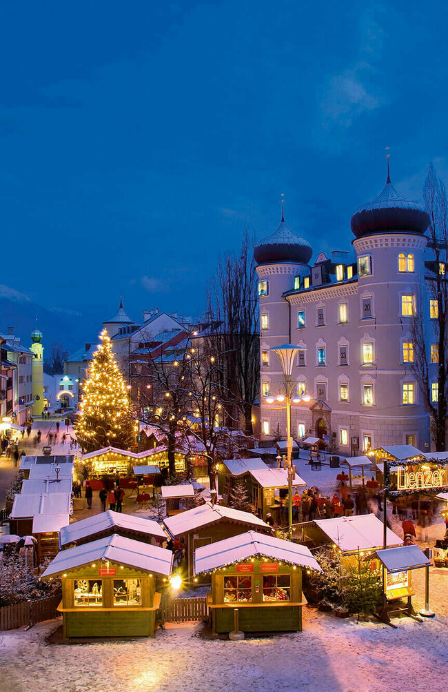 Beleuchteter Adventmarkt am Hauptplatz in Lienz in frühabendlicher Stimmung.