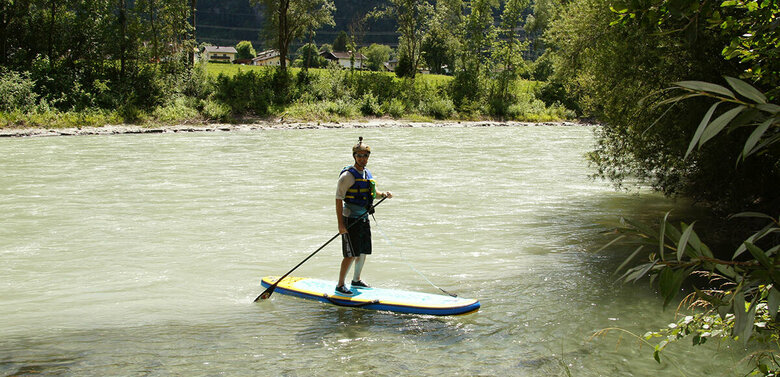 Stand Up Paddle Eine Person mit Schwimmweste und Helm steht auf einem Stand Up Paddle Board auf der Isel.