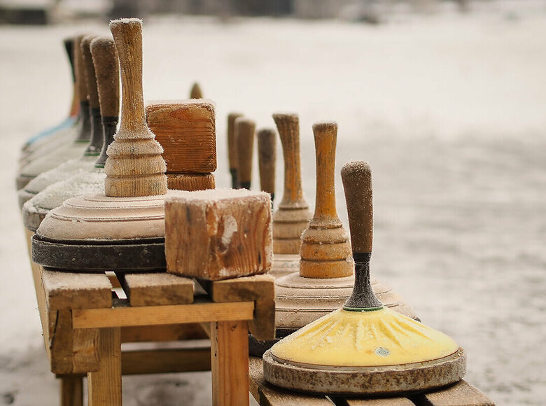 Eine hölzerne Bank voll Equipment zum Eisstockschießen.