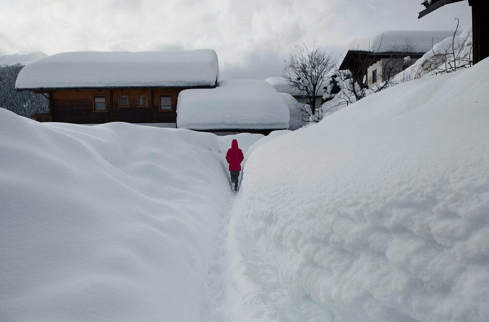 Eine Person schaufelt sich durch die hohen Schneewände in Obertilliach einen Weg frei.