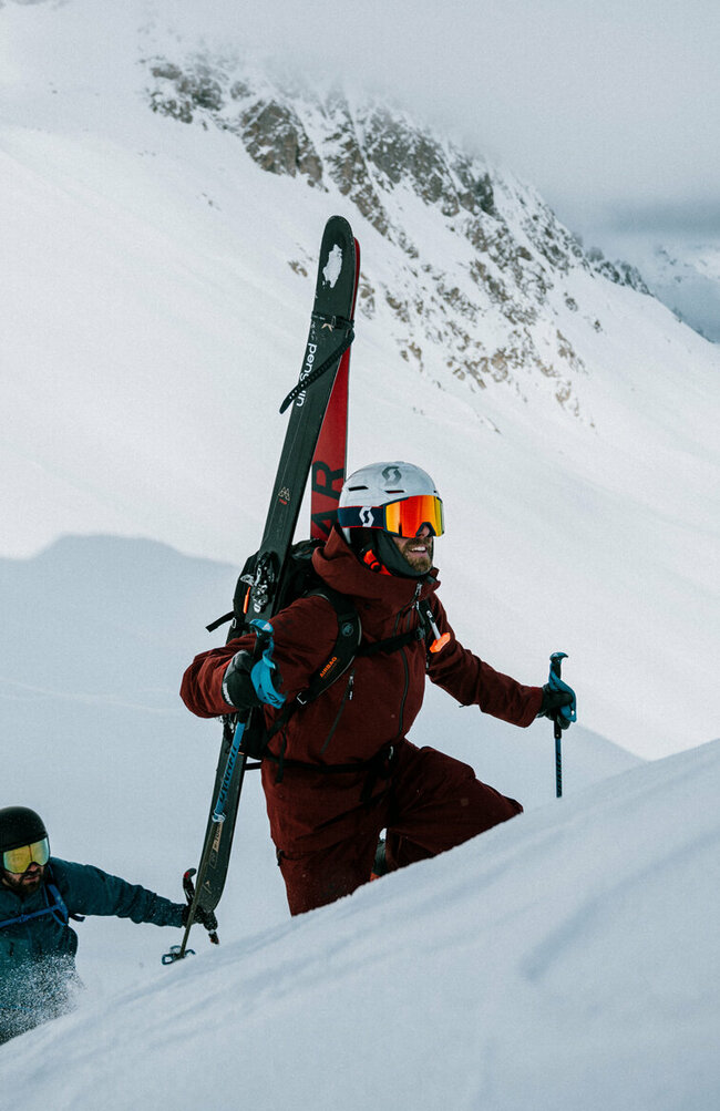 Das Ziel vor Augen. Zwei Skitourengeher befinden sich in einem Steilhang auf ihrer Skitour im Defereggental. Sie tragen ihre Tourenski am Rücken und blicken ihrem Ziel motiviert entgegen.