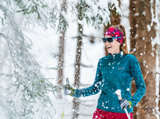 Frau beim Langlaufen in Obertilliach im verschneitem Wald