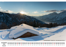 Die unberührte Schneelandschaft im Debanttal, eine Hütte liegt unter einer dicken Schneeschicht und die Sonne glänzt hinter dem Horizont hervor. 