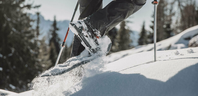 Die Beine eines Mannes beim Schneeschuhwandern durch den Tiefschnee.