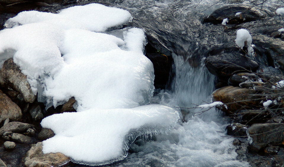 Ein Bach, der trotz eisigen Verhältnissen und einigen Schneeflecken noch fließt.