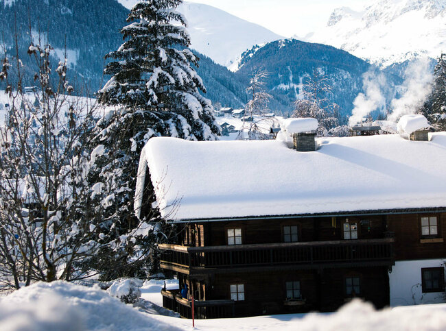 Blick auf eine verschneite, dunkle Holzhütte im Winter im Defereggental.