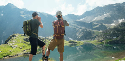 Zwei Wanderer stehen am Geigensee im Defereggental in Osttirol und rufen einen "Juchizer" aus.