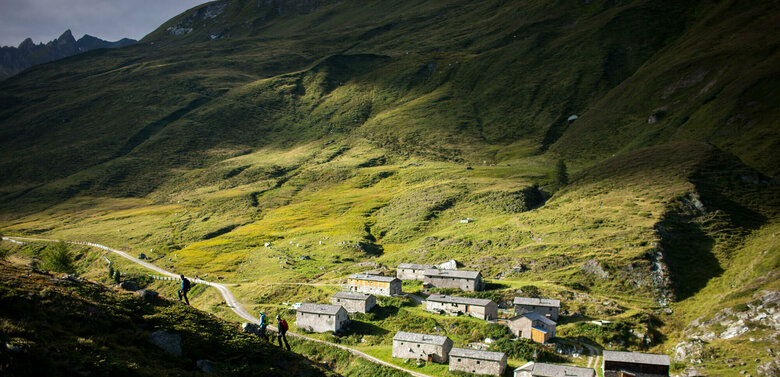 Mehrere alte Gebäude der Jagdhausalmen stehen sanft eingebettet in Osttiroler Landschaft.