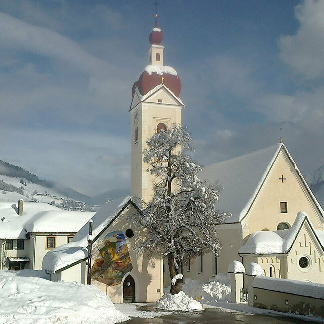 Die Asslinger Kirche mit umgebenden Häusern ist tief mit Schnee bedeckt im Winter.