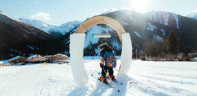 Kleiner Skifahrer führt durch Bogen im Kinderland in Obertilliach